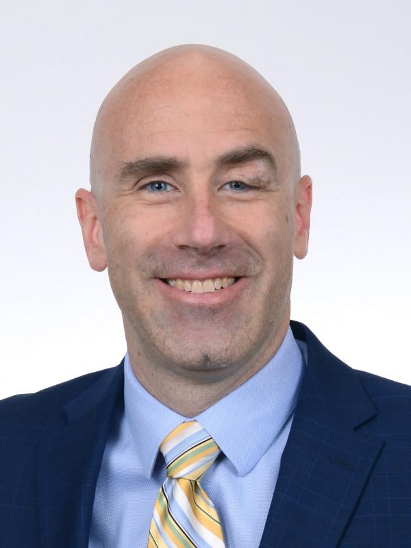 Professor Poirier smiling with a white background