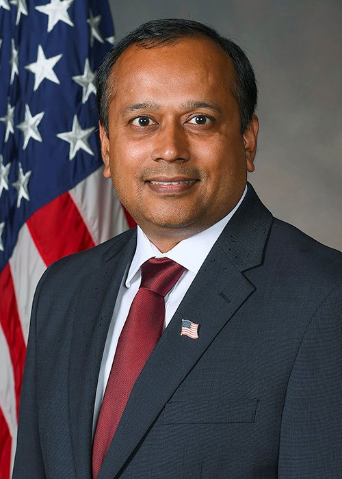 Photo of Anil Patnaik with plain grey background and American flag