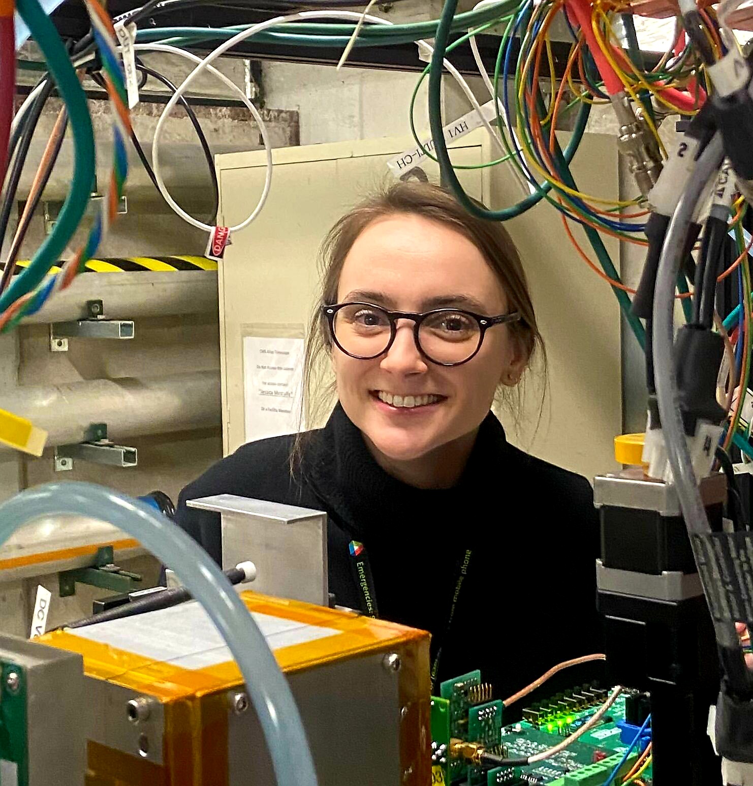 Photo of Maria Zurek in her lab, surrounded by wires and equipment