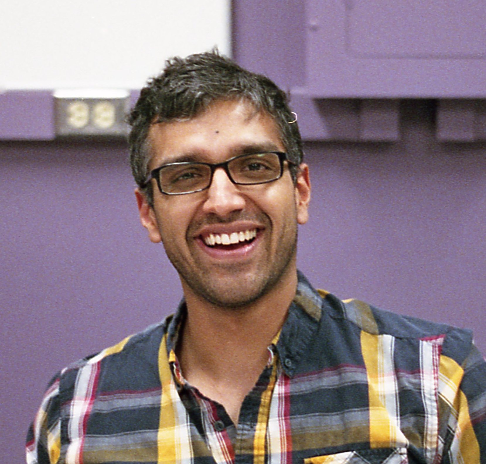 Headshot of Kevin Singh with purple wall behind him