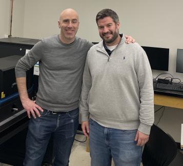 Photo of Michael Poirier and Carlos Castro standing side by side in lab and smiling