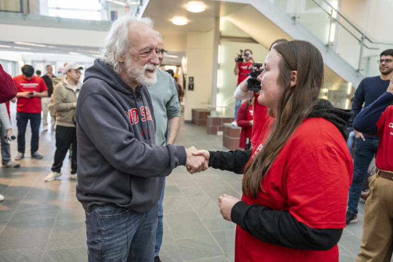 Pierre Agostini shaking hands with a student in the PRB Atrium