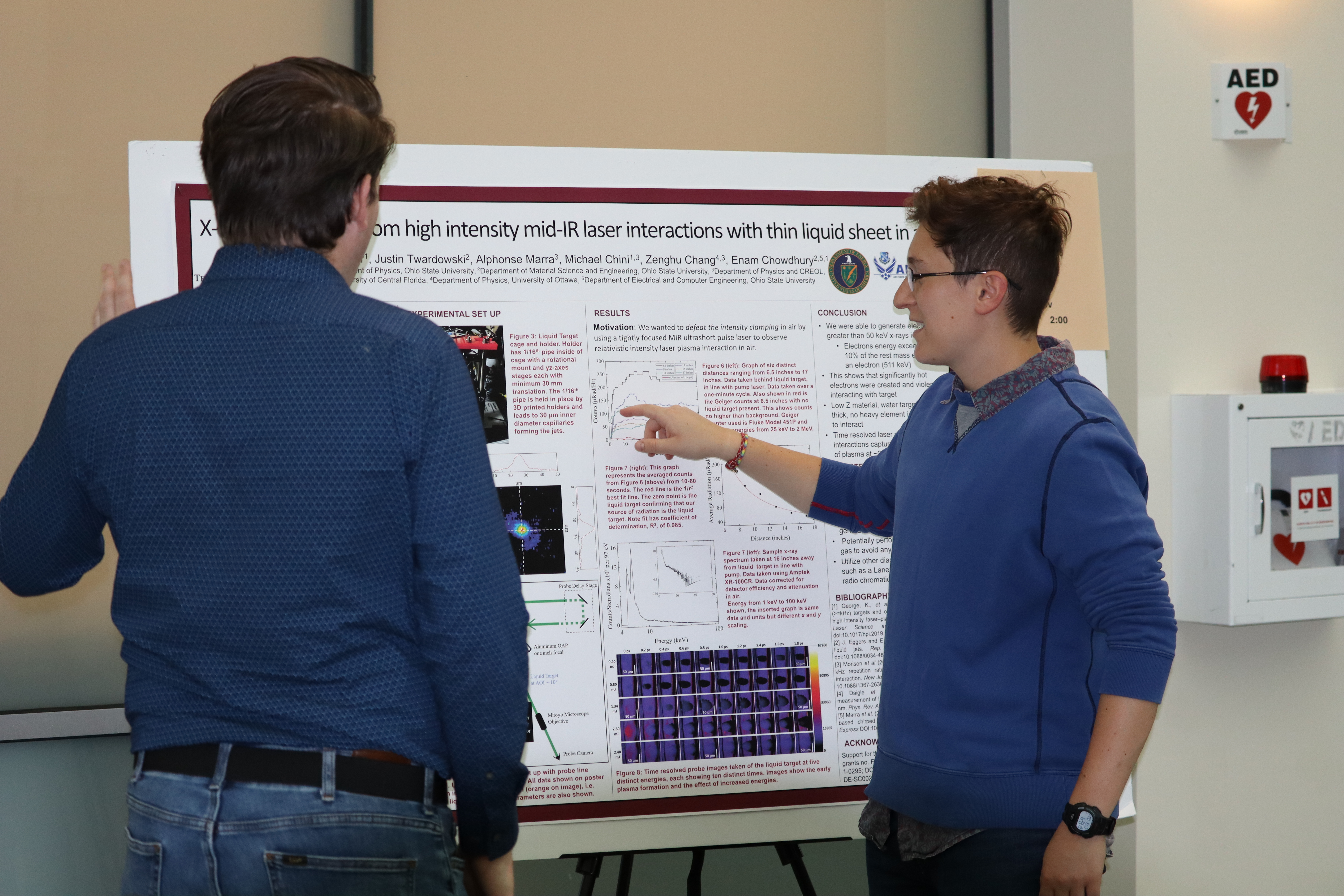 Student pointing and discussing his research poster