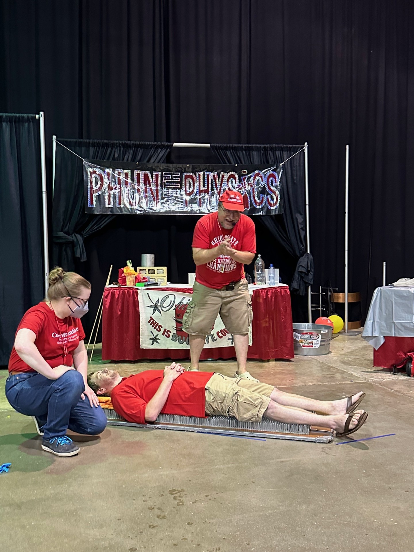 Man in a red shirt laying on a bed of nails