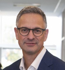 Job Dekker smiling slightly with bright window behind him