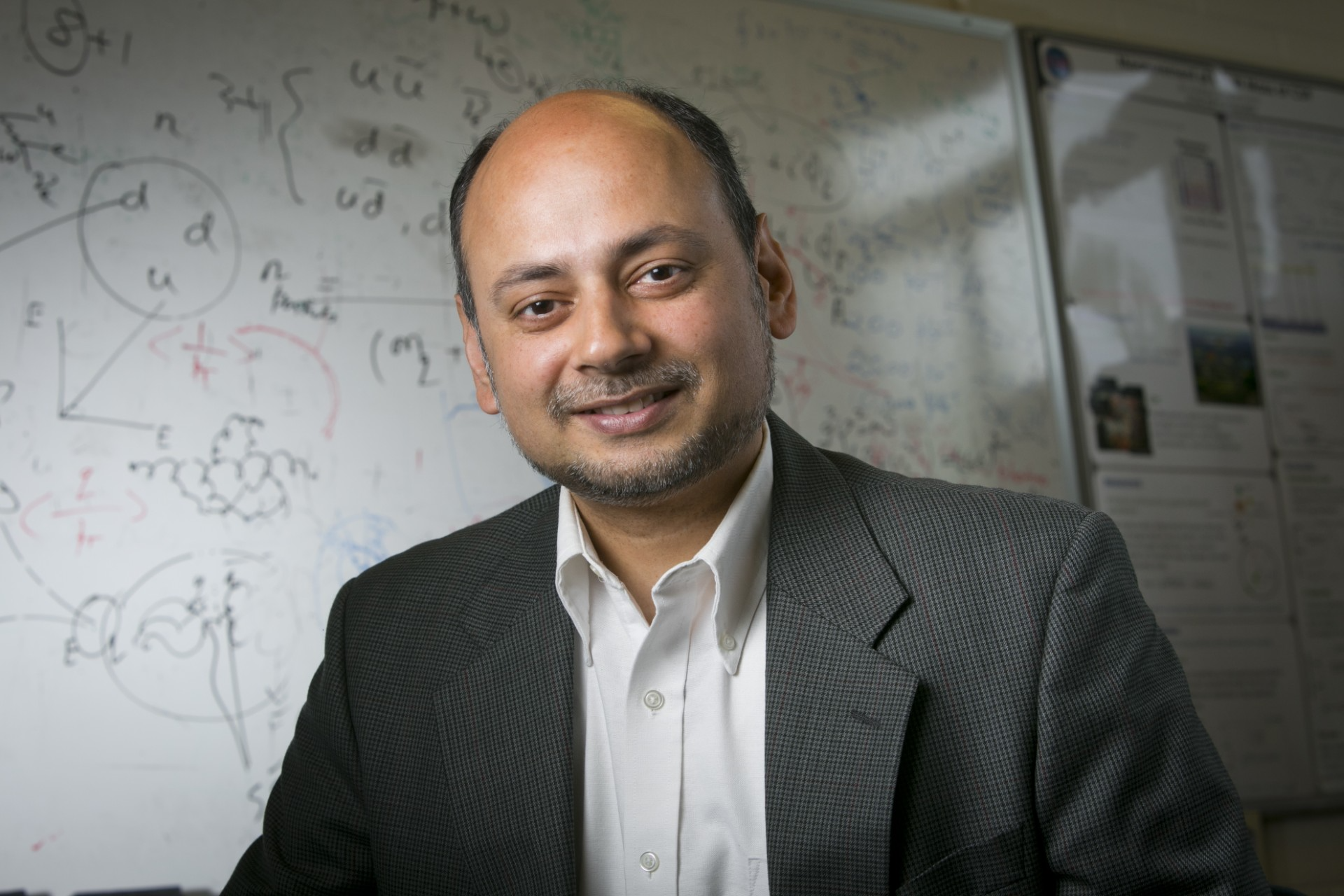 Ashutosh Kotwal standing in front of a whiteboard covered in equations