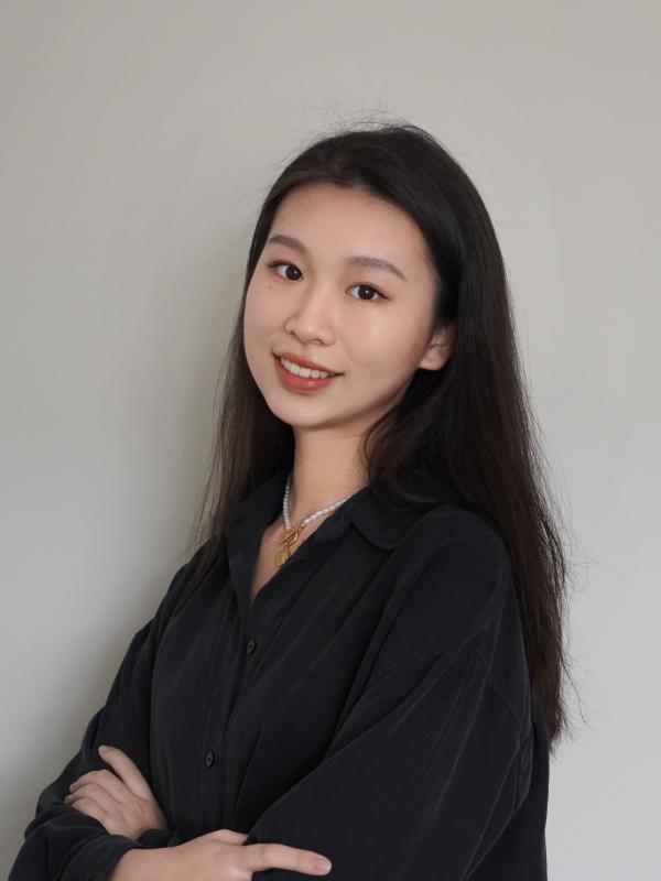 Yuxin Standing with arms folded in front of a white wall