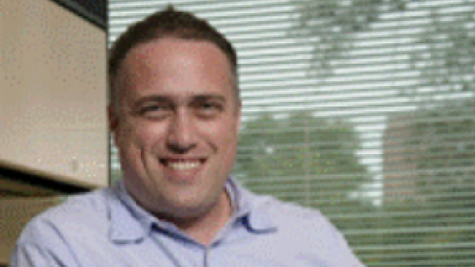 Ezekiel Johnston-Halperin smiling in his office with window behind him