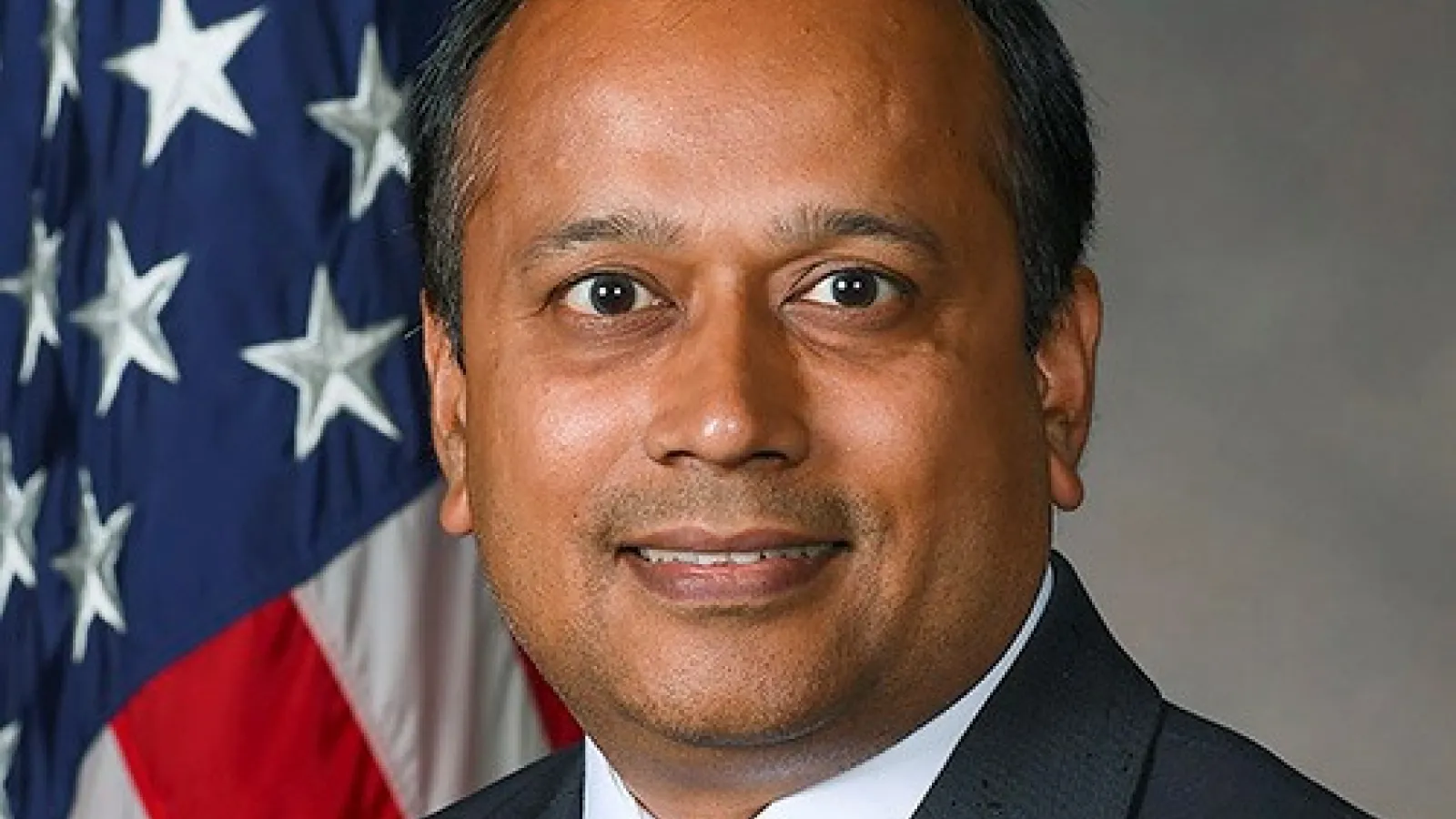 Anil Patnaik with plain grey background and American flag