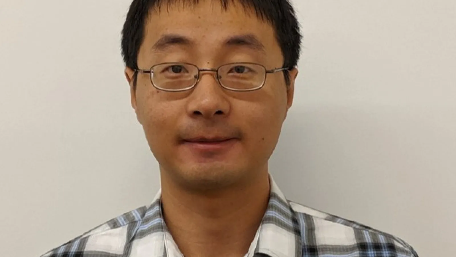 Headshot of Han Zhao with beige wall behind him