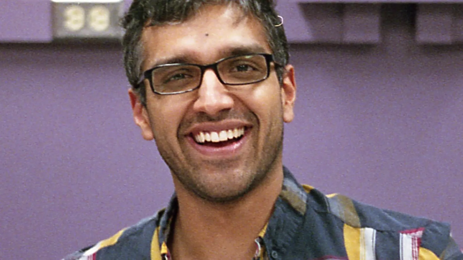 Headshot of Kevin Singh with purple wall behind him