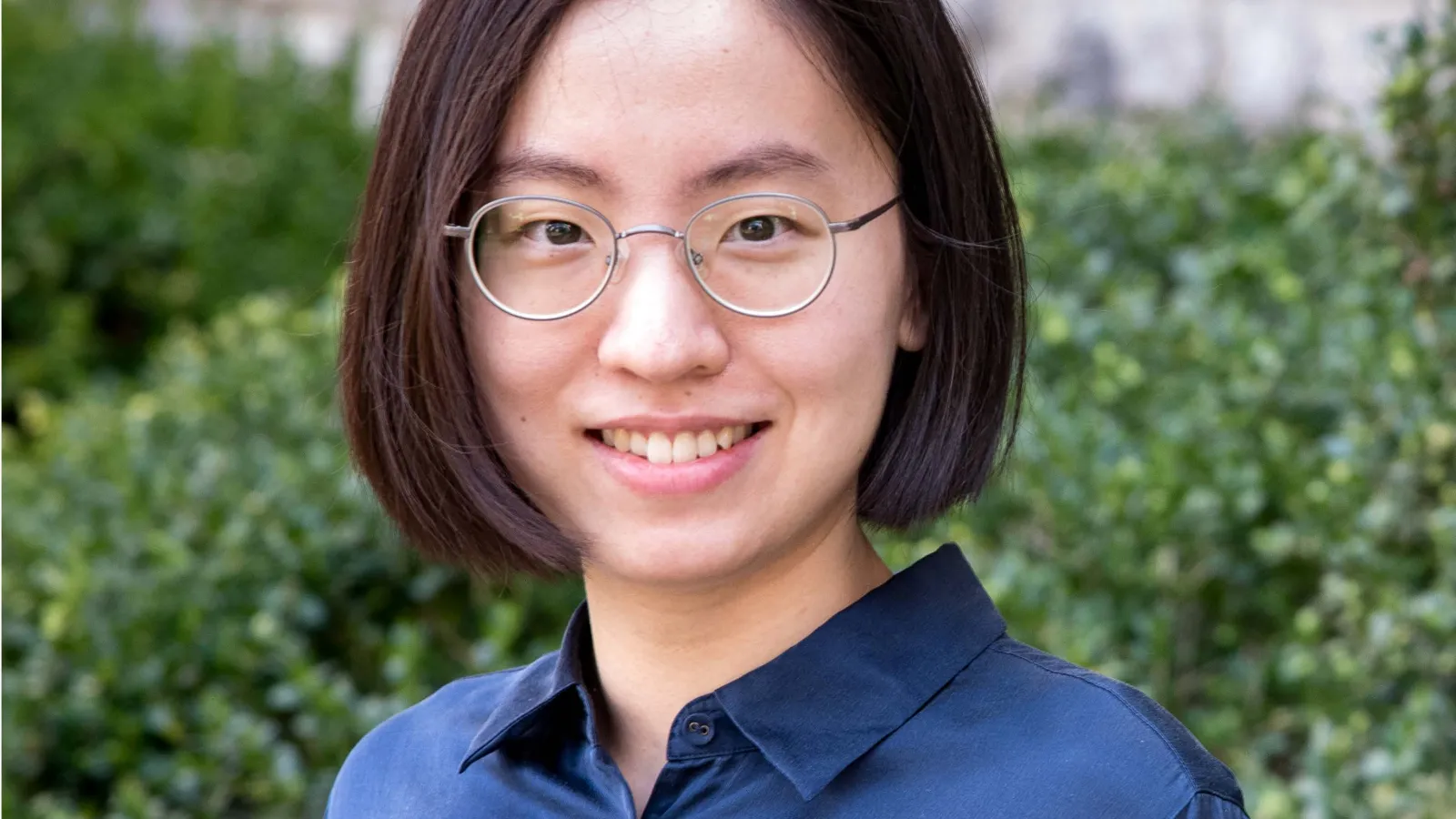 Headshot of Yanzhu Chen with shrub and wall in the background