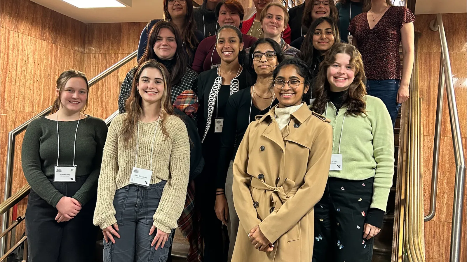 Students smiling and standing on stairs at conference 