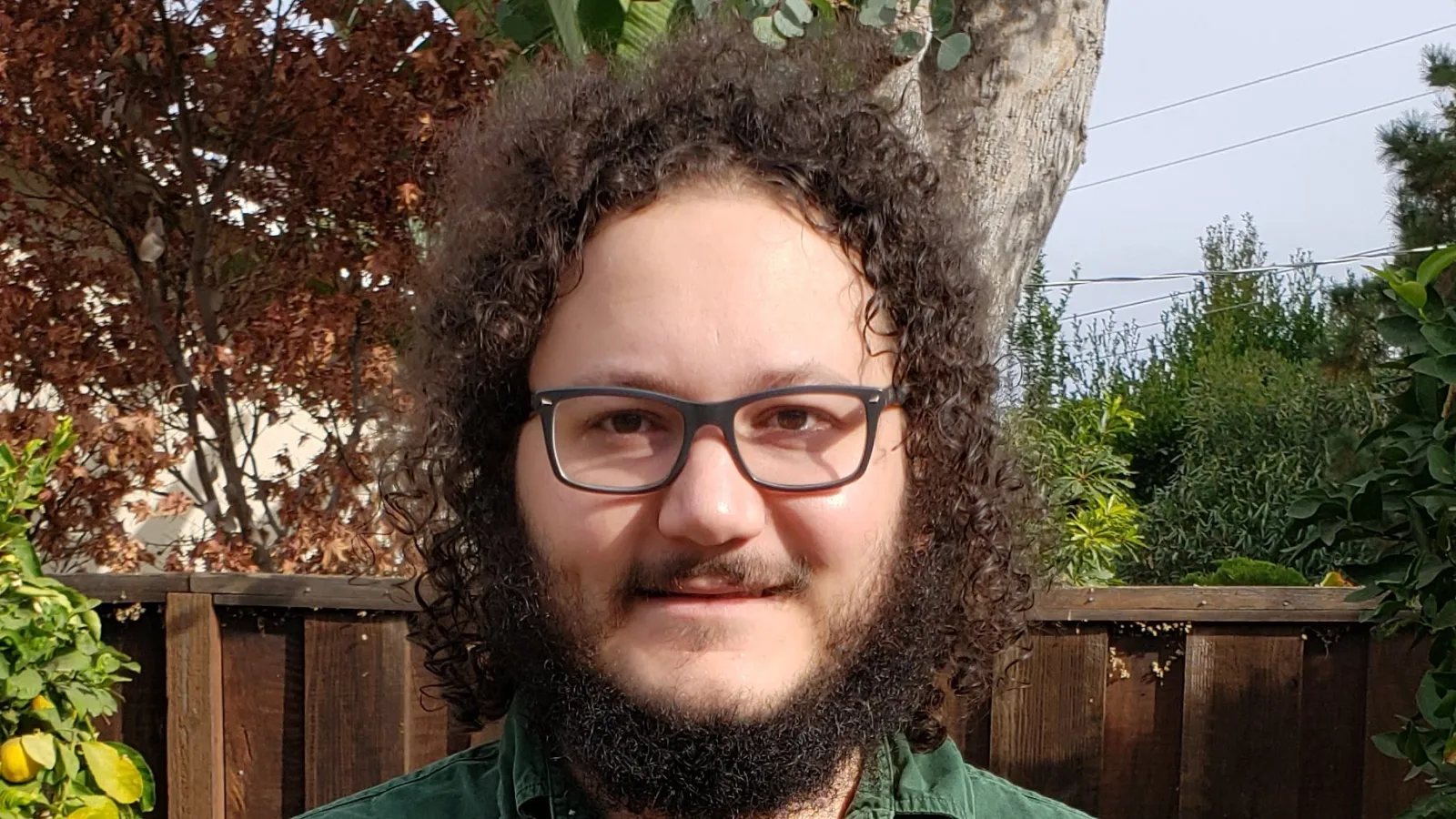 Headshot of Cameron Bravo with yard and fence in the background.