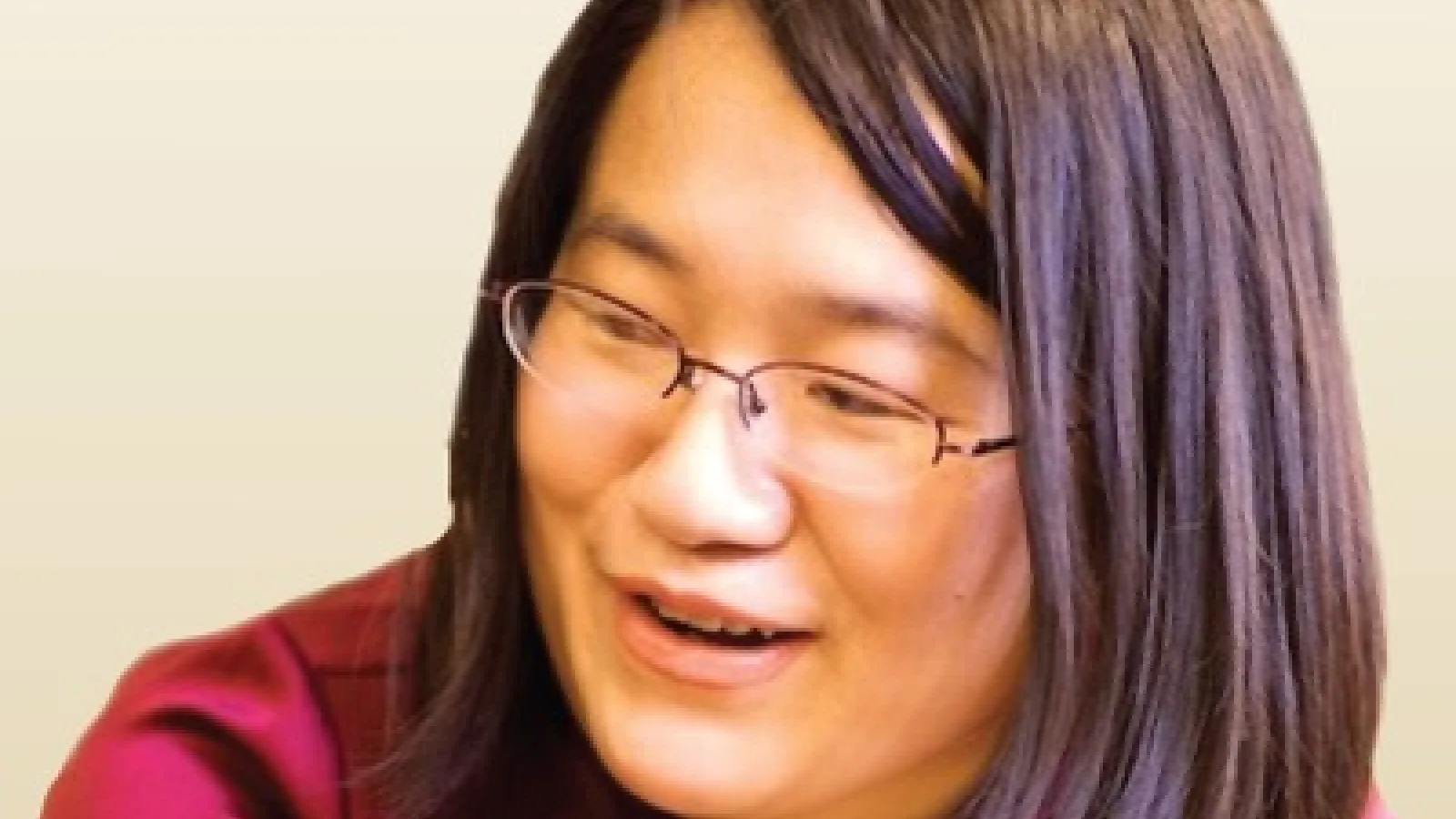 Jeanie Lau speaking with beige wall in background