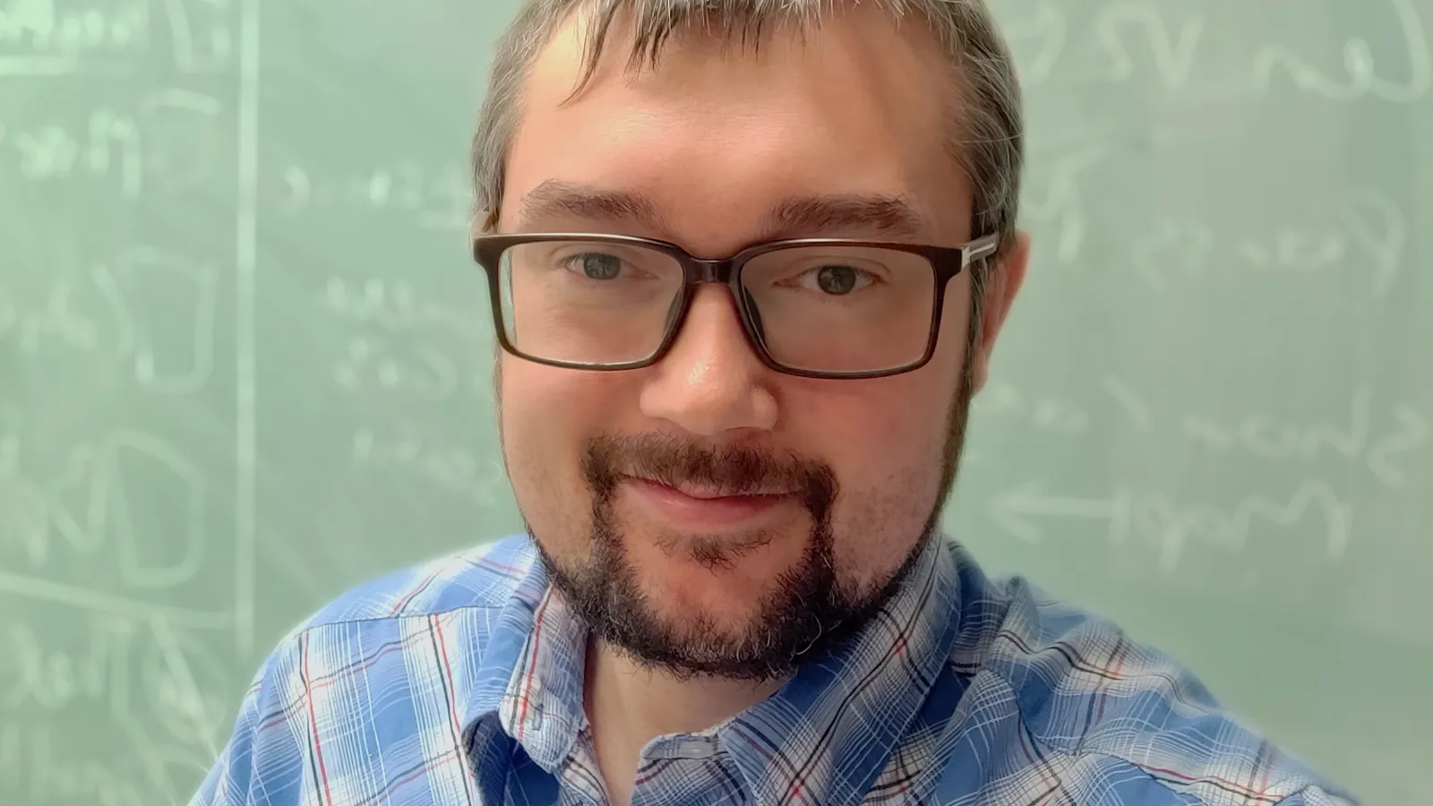 Headshot of Mark Ross-Lonergan with chalkboard in the background