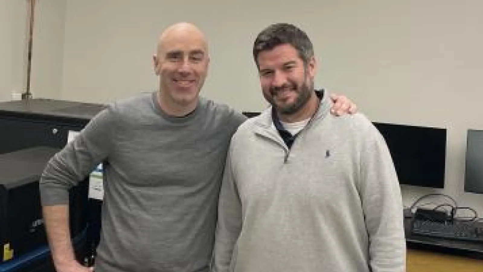 Michael Poirier and Carlos Castro standing side by side in lab and smiling