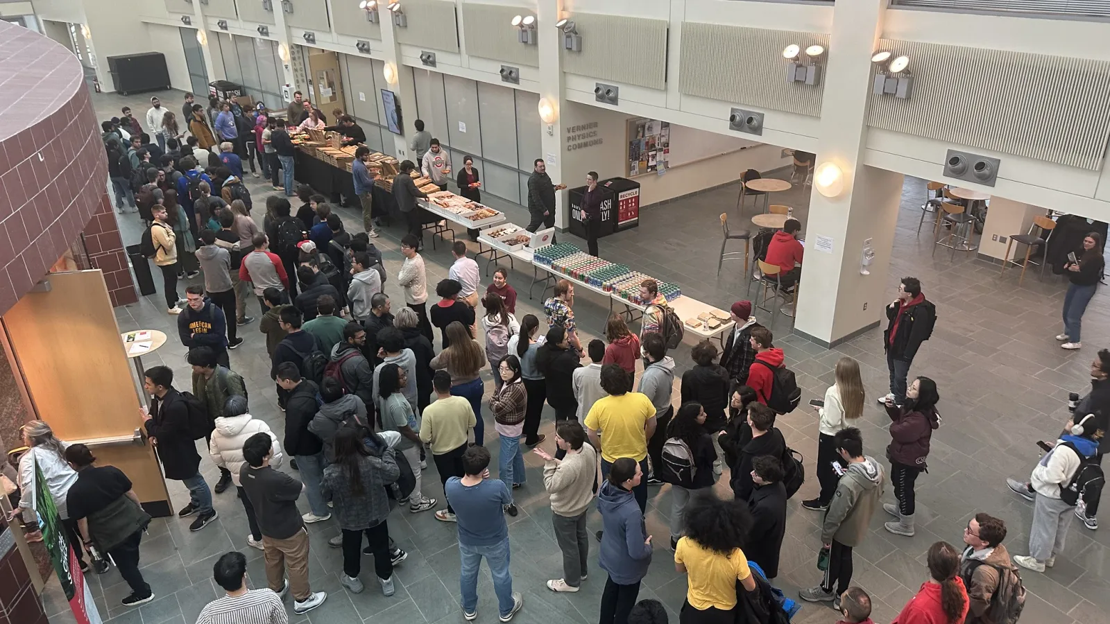Aerial view looking down on atrium at crowd of students in line for food and to meet Pierre Agostini.