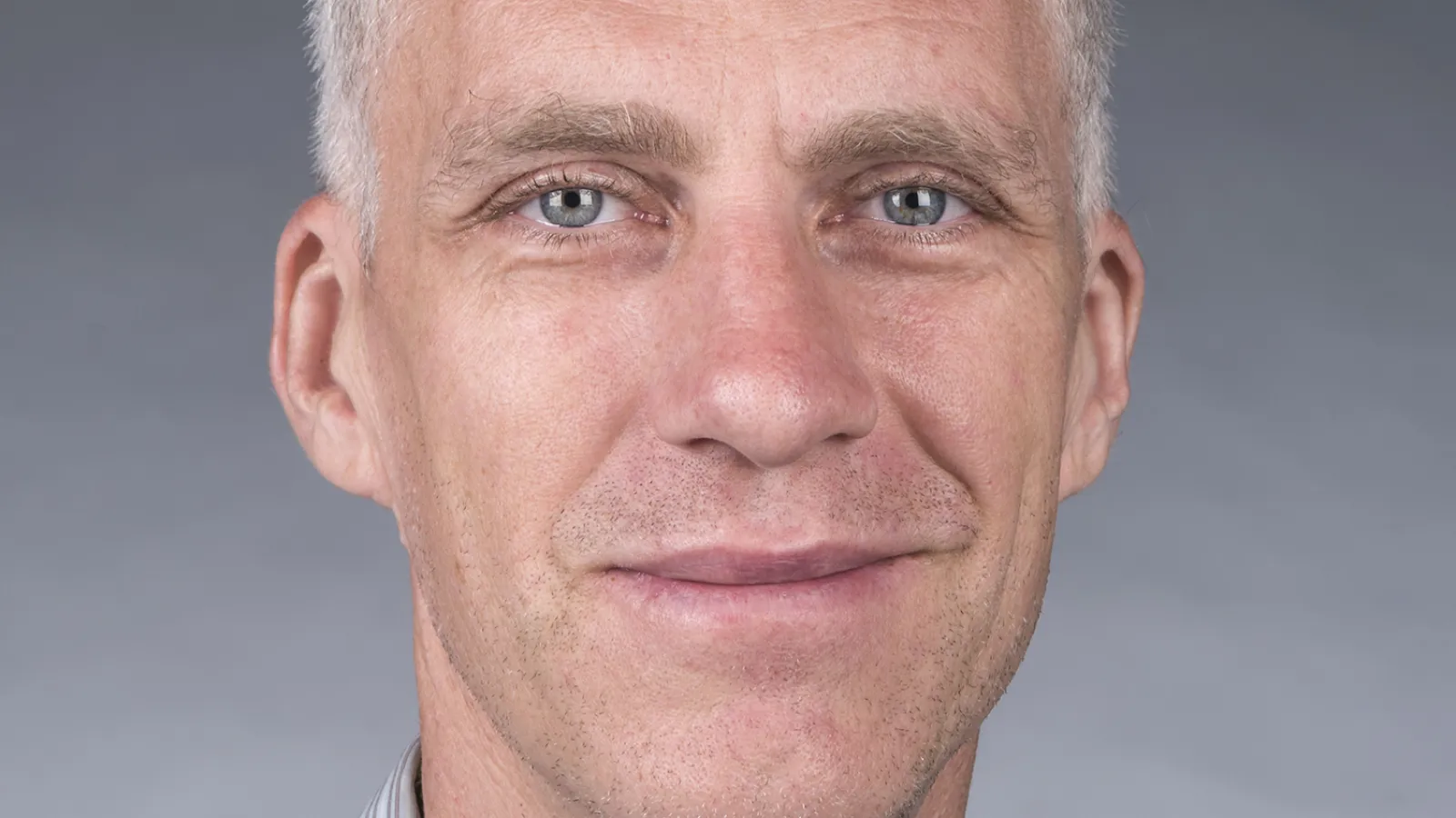 David Brookes smiling with plain grey background