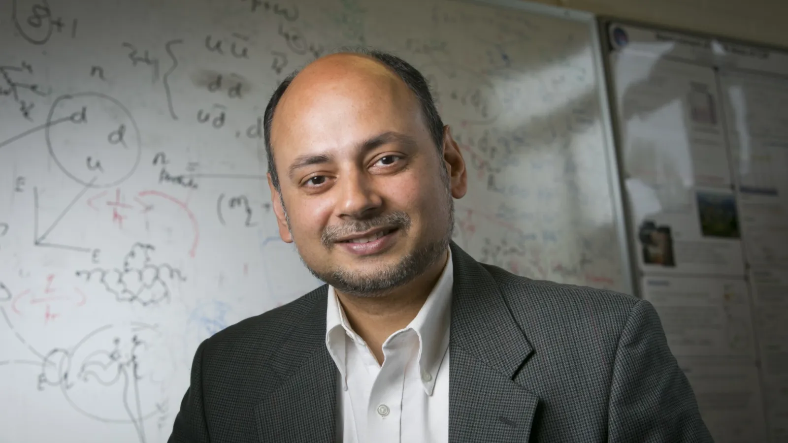Ashutosh Kotwal standing in front of a whiteboard covered in equations