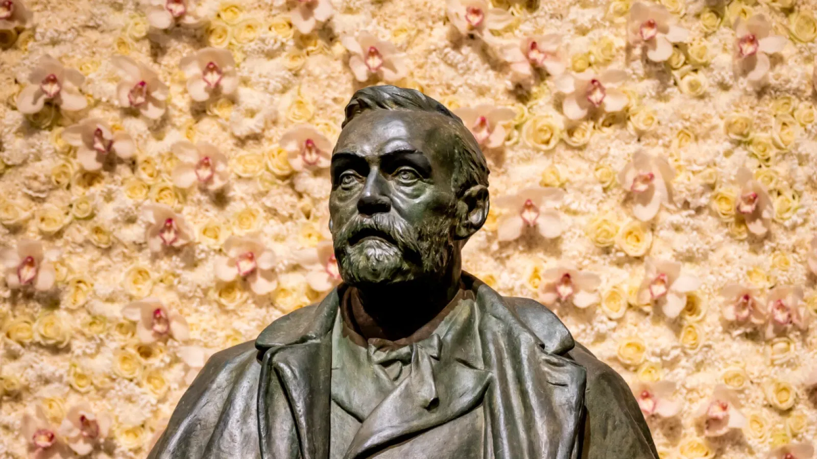 Statue of Alfred Nobel with flowers behind him