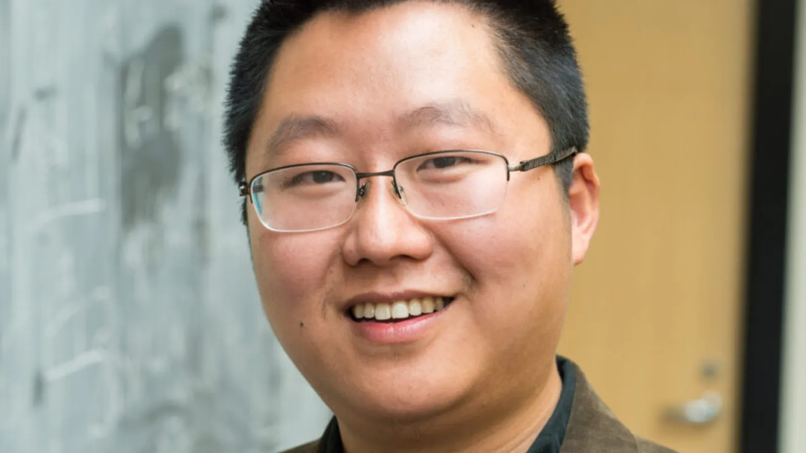 Liang Fu smiling in front of a door