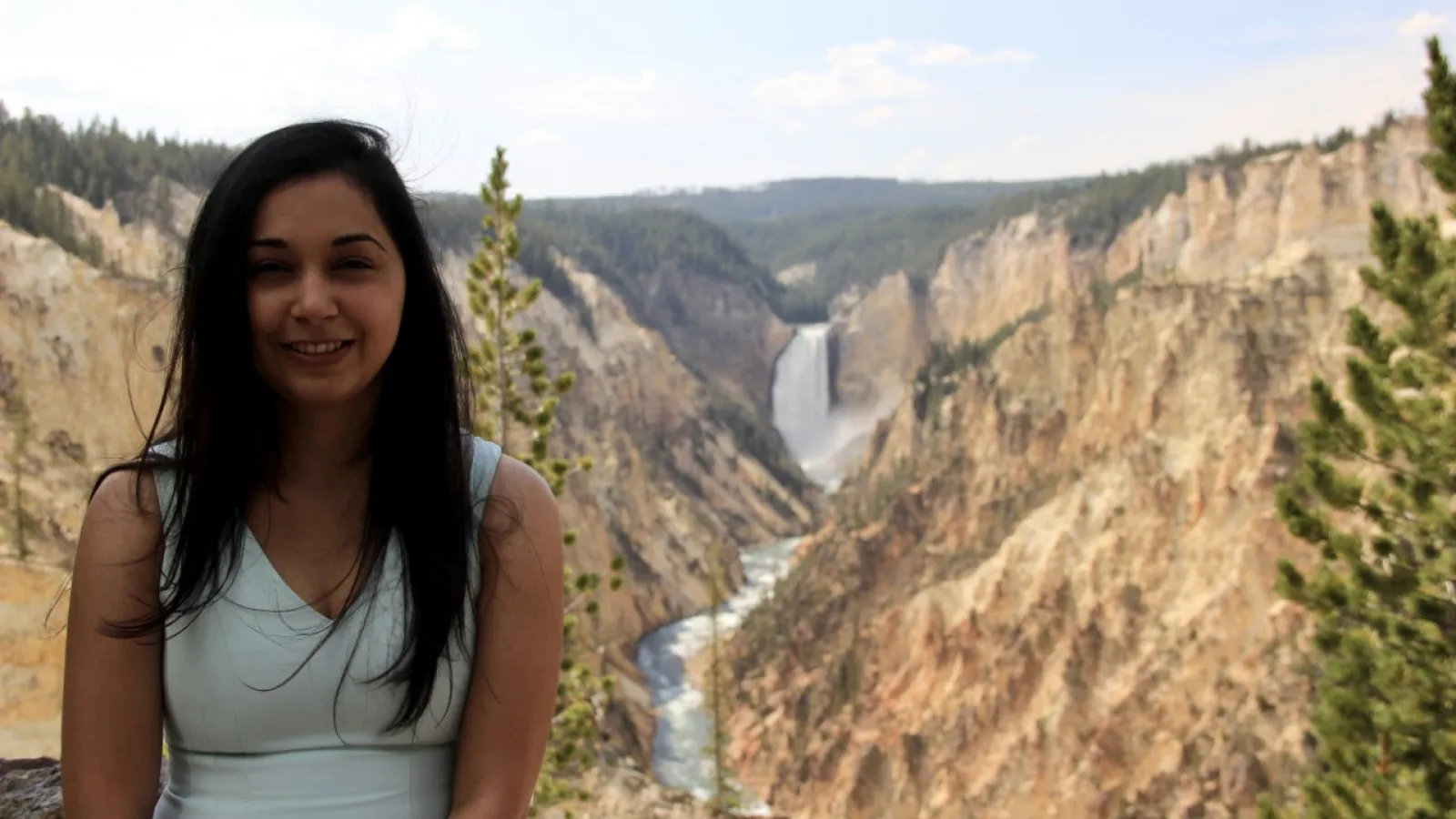 Niharika smiling in front of a canyon with a waterfall in the distance