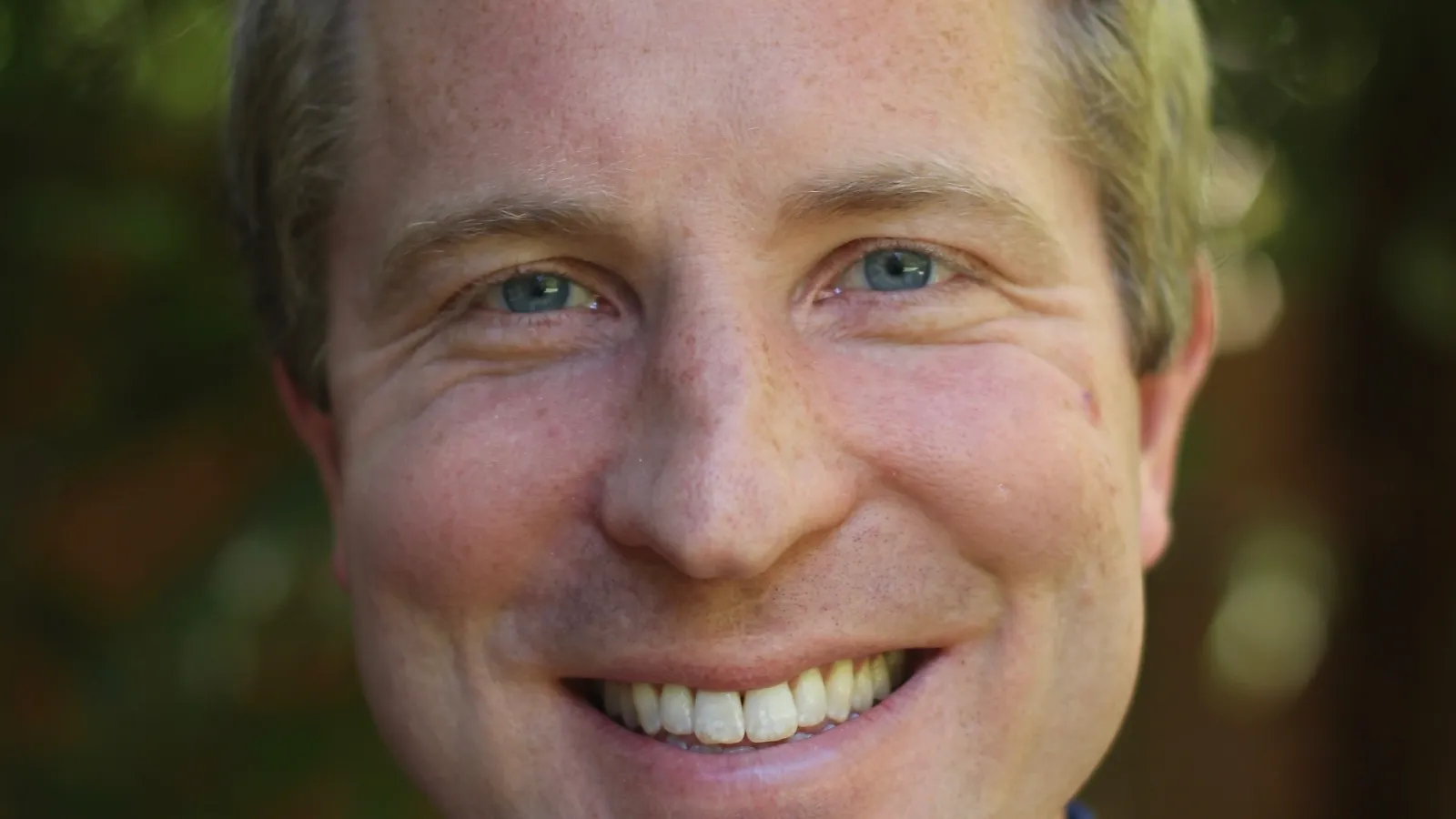 Close up of Peter in front of a blurred out leafy background