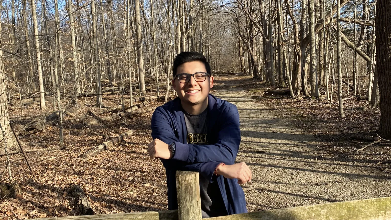 Mat Leon standing on a wooded path and leaning on a fence