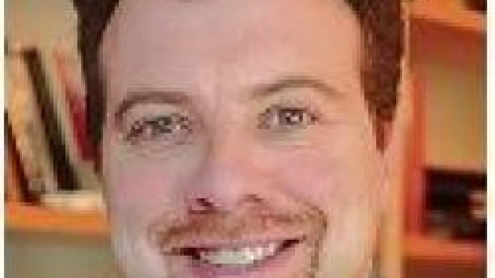 A close-up of Adam Riess with a bookshelf in the background.