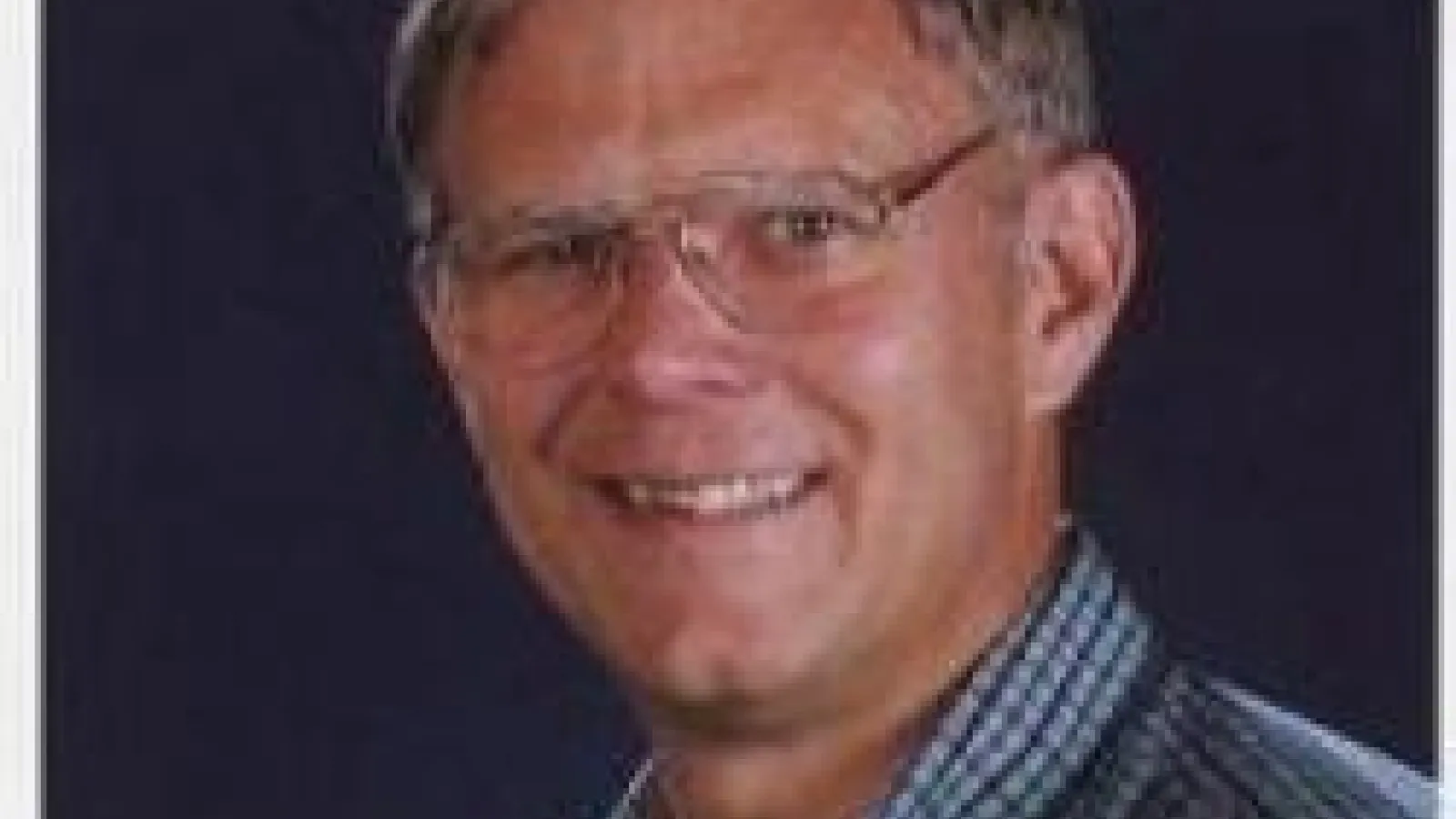 Eric Braaten smiling with navy blue background