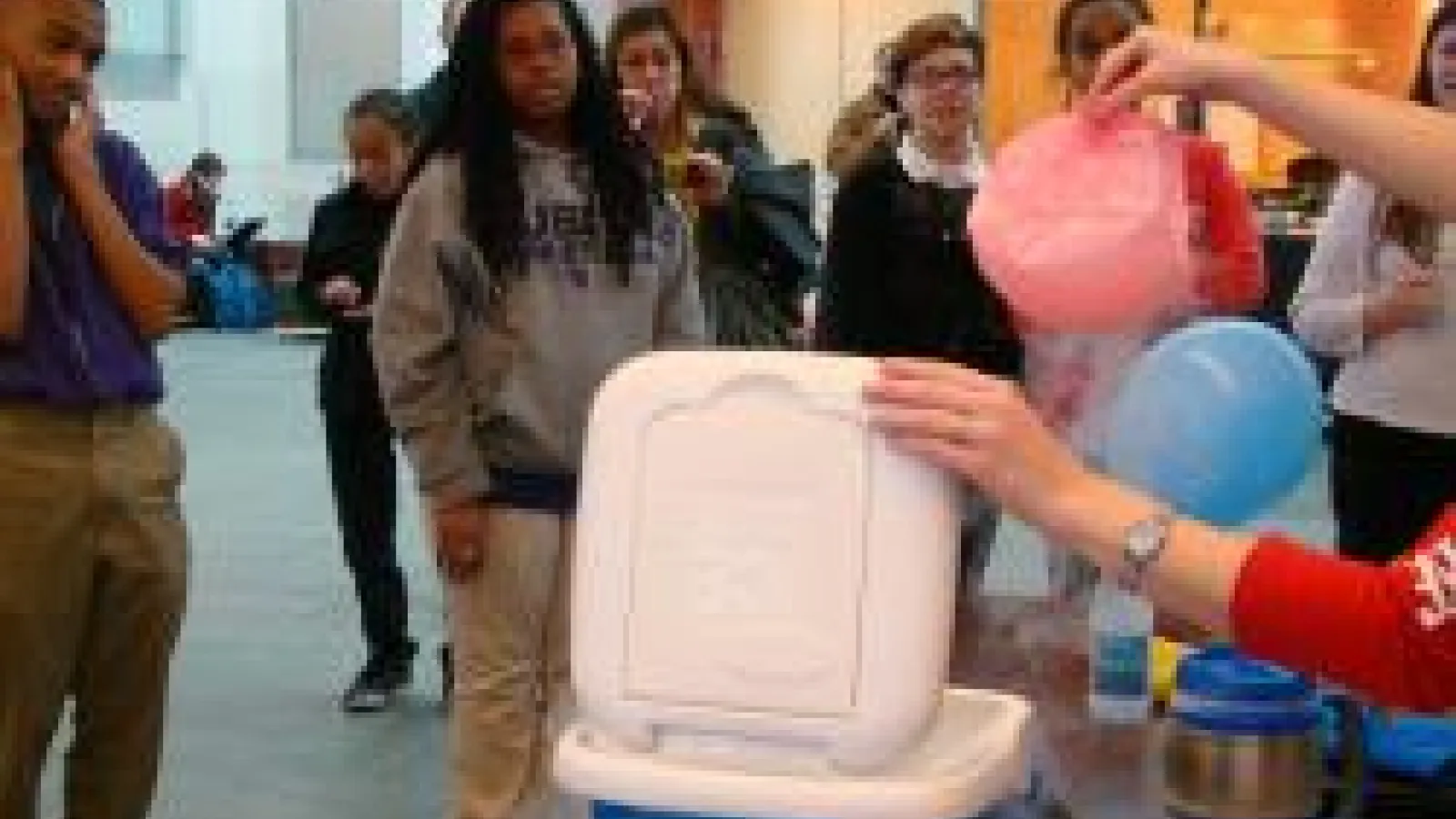 Students watching balloons being put in a frozen cooler