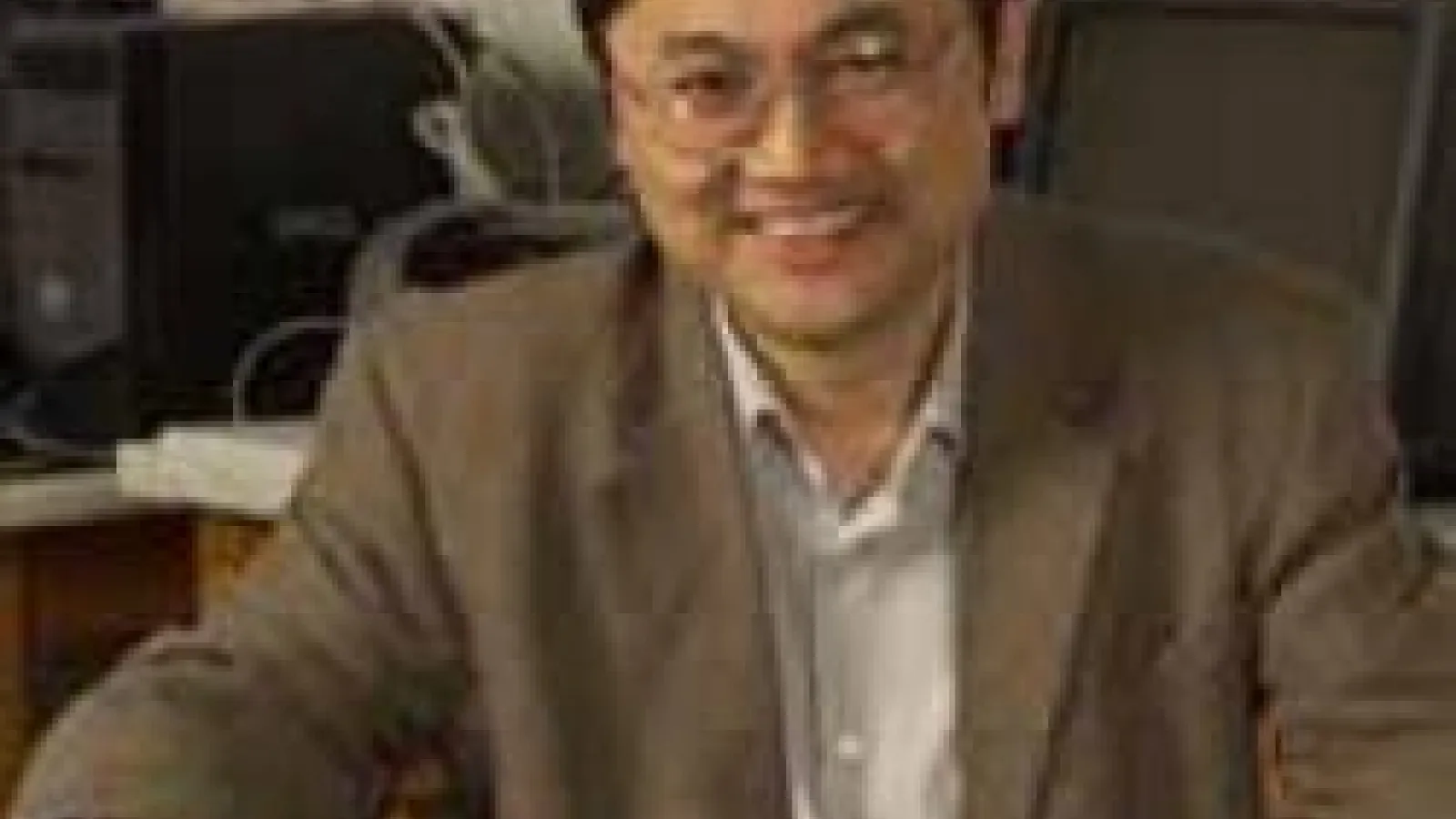 Dongping sitting on chair and smiling with computers in the background