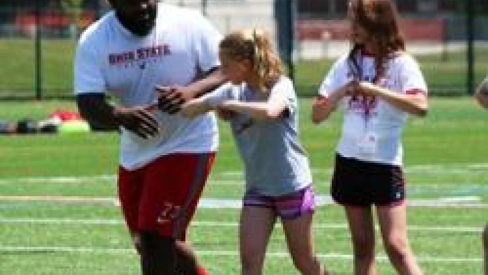 Two students on field with OSU football player