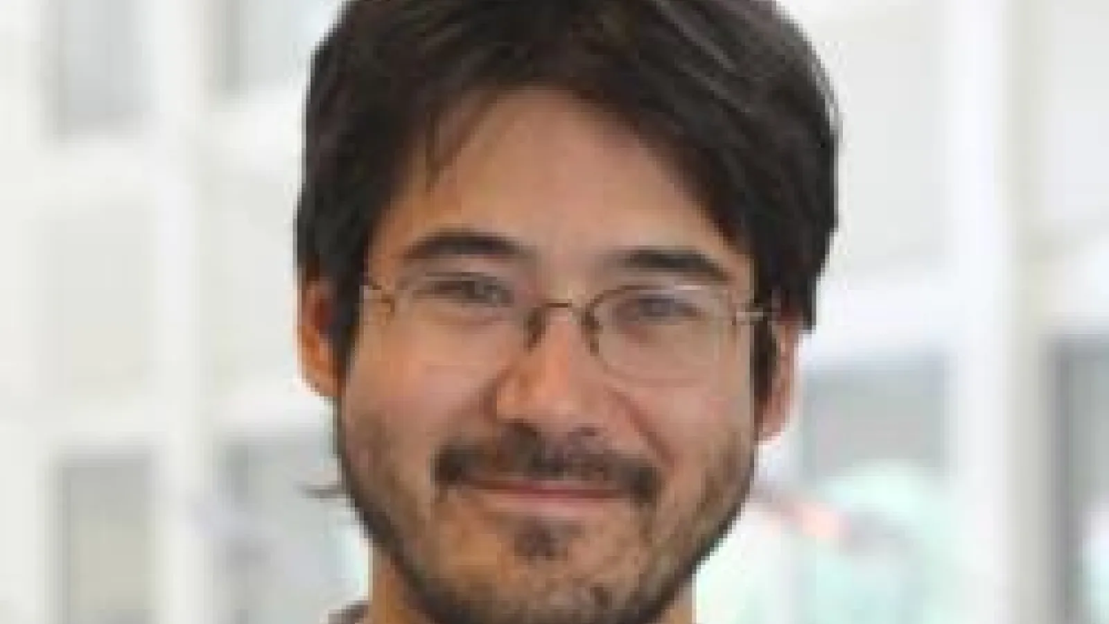 Chris Hirata smiling with blurred out PRB atrium in the background