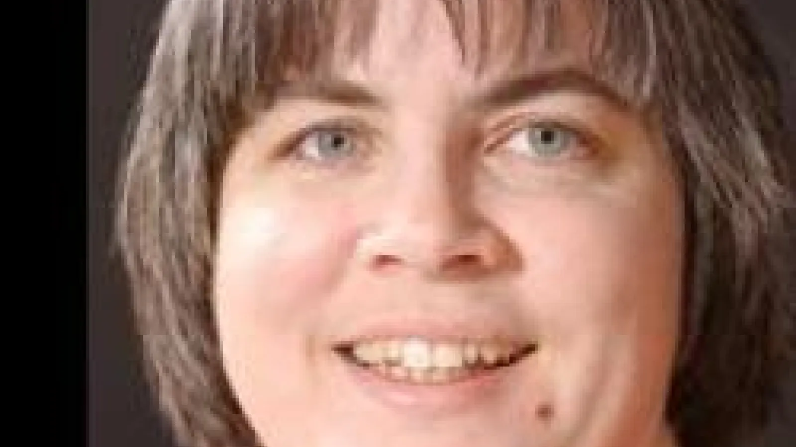 Kathleen Falconer smiling with plain grey background