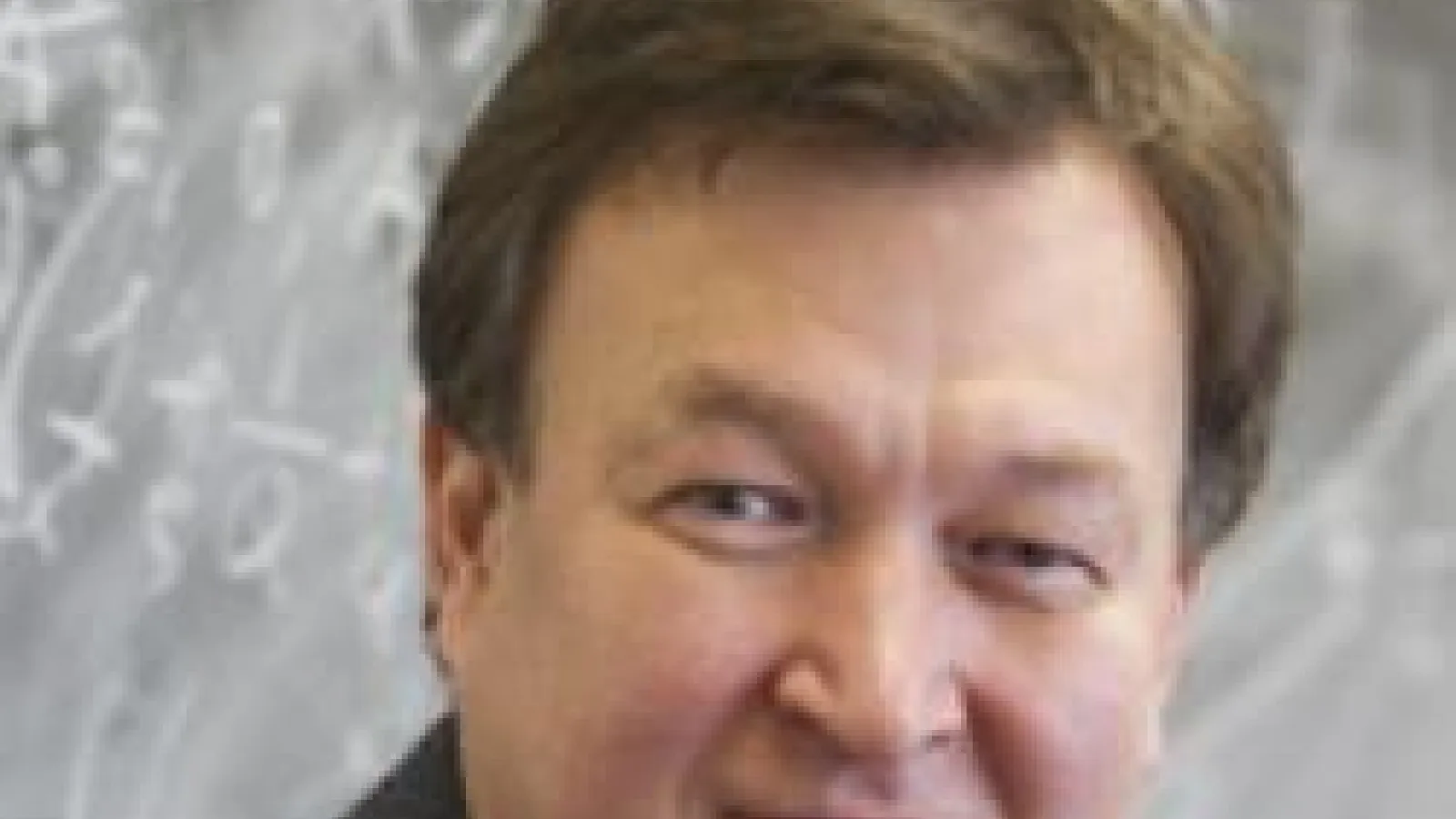 Dmitri Kharzeev with chalkboard behind him