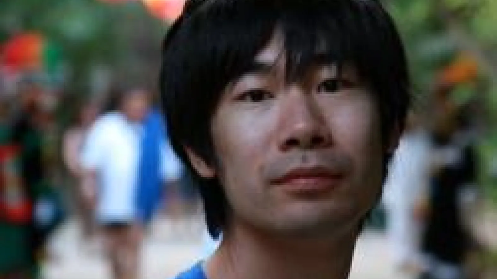 A close-up of Weiran Li with a blurred background of people walking.