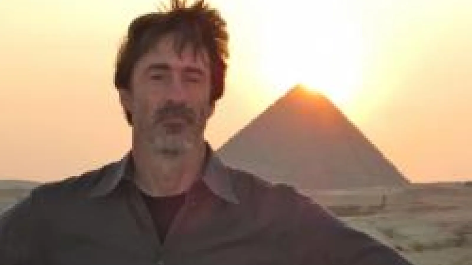 Mike with hands on hips standing in the desert in front of the great pyramids