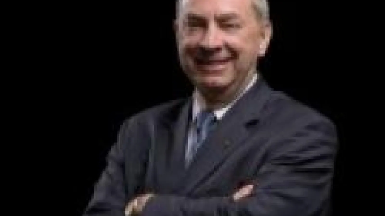 Nigel Lockyer smiling with arms crossed over chest, on black background