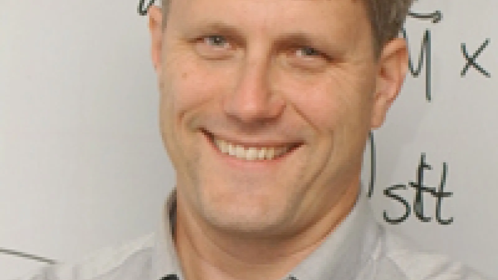 Mark D. Stiles smiling with whiteboard in the background