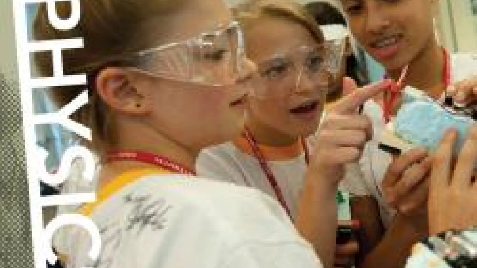 Students in protective goggles talking and working on an experiment