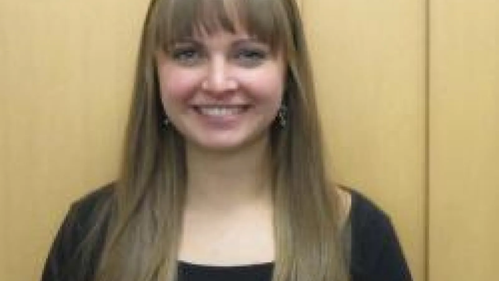 Rebecca Reesman smiling with wood panel background