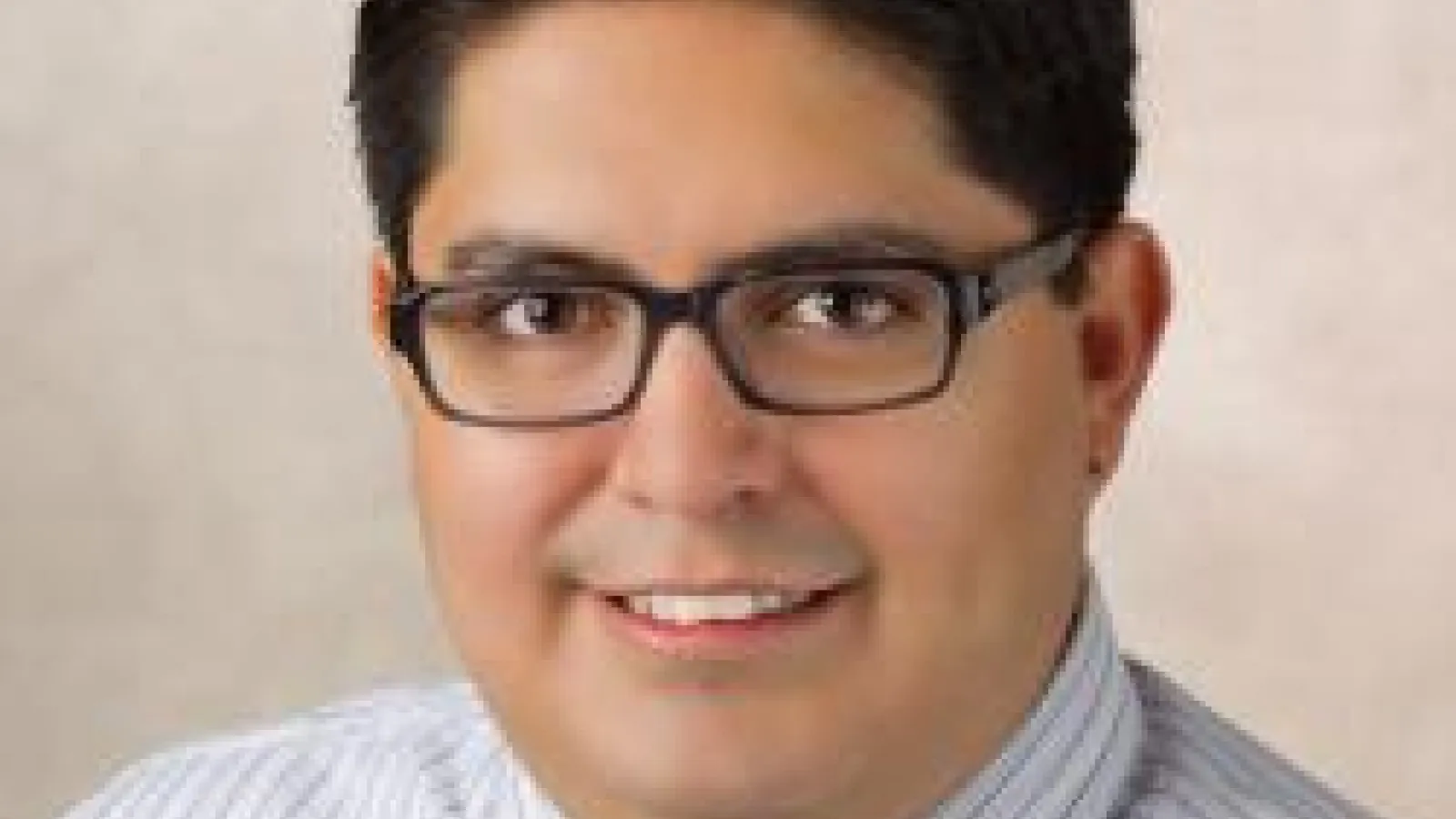 A headshot of Rolando Valdes Aguilar with a cream background.