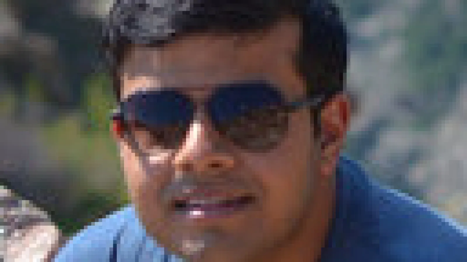 D Chowdhury in sunglasses sitting on a rock