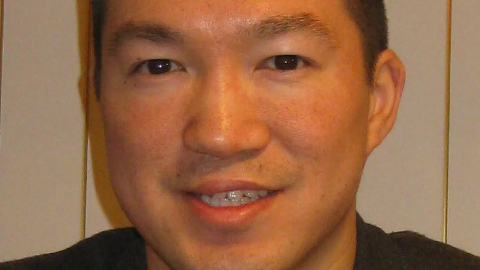 Eric Feng smiling in front of striped wall
