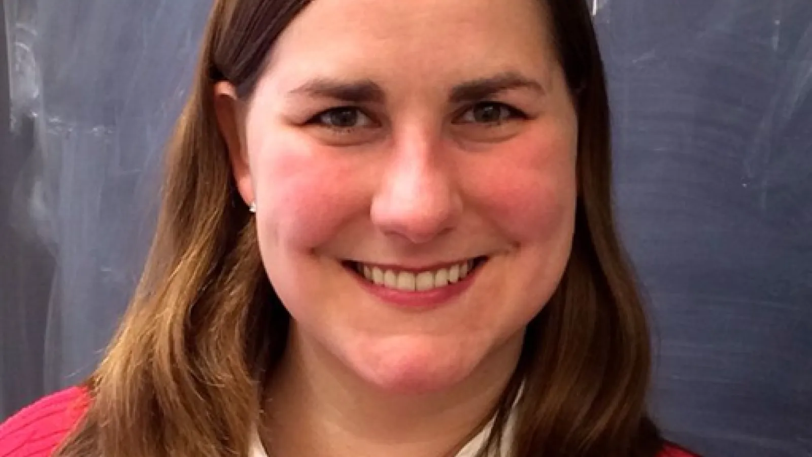 Adrienne Erickcek smiling with empty blackboard behind her