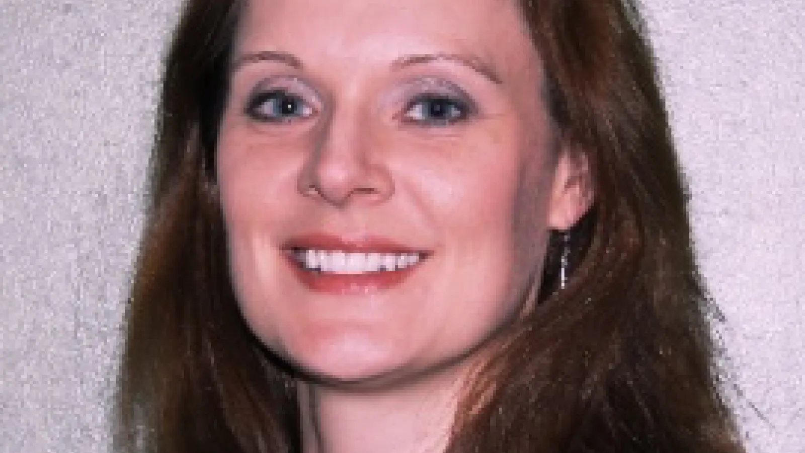Kelly Denney smiling with light grey background