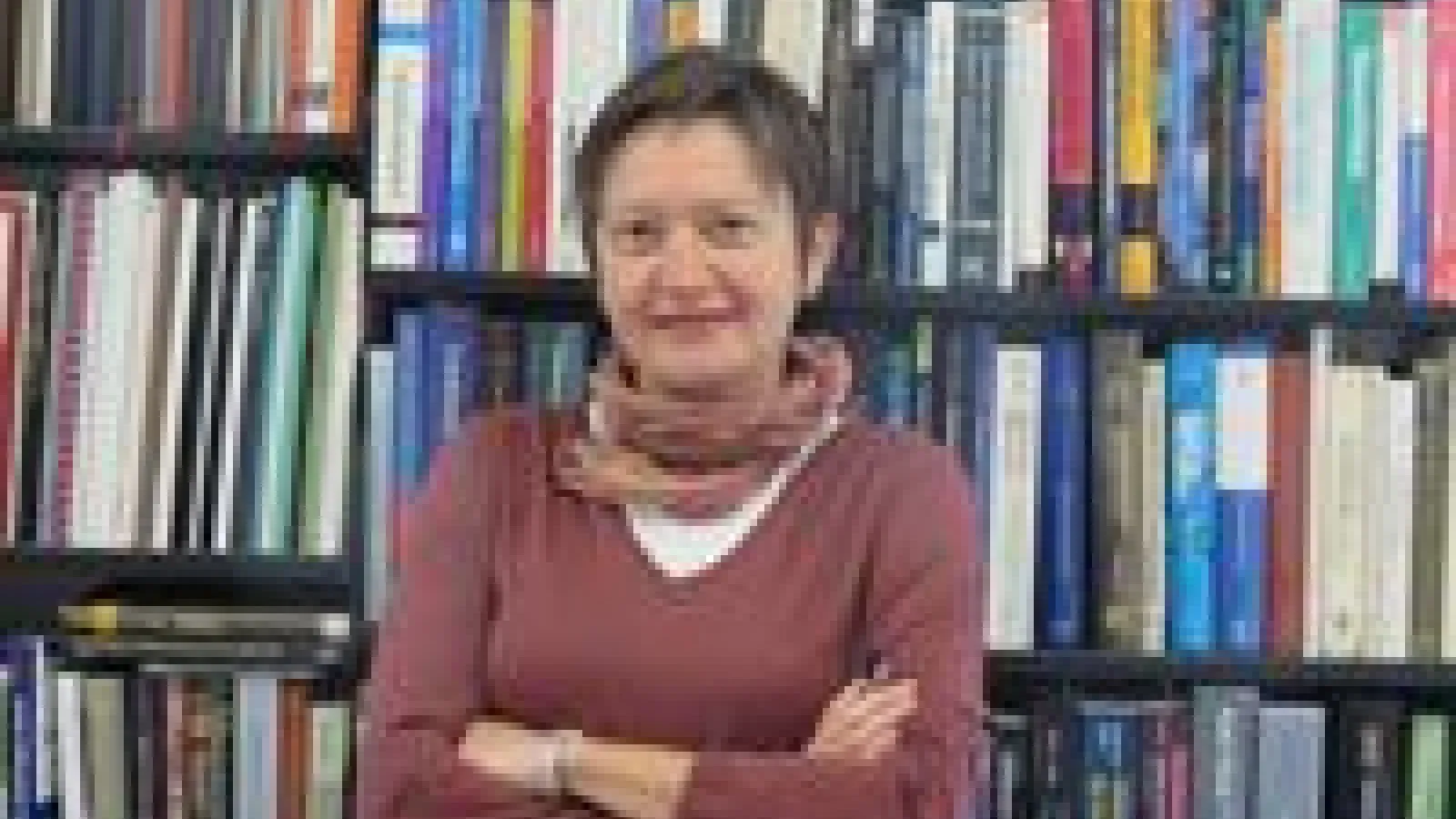 Vesna Mitrovic with arms crossed in front of bookshelves