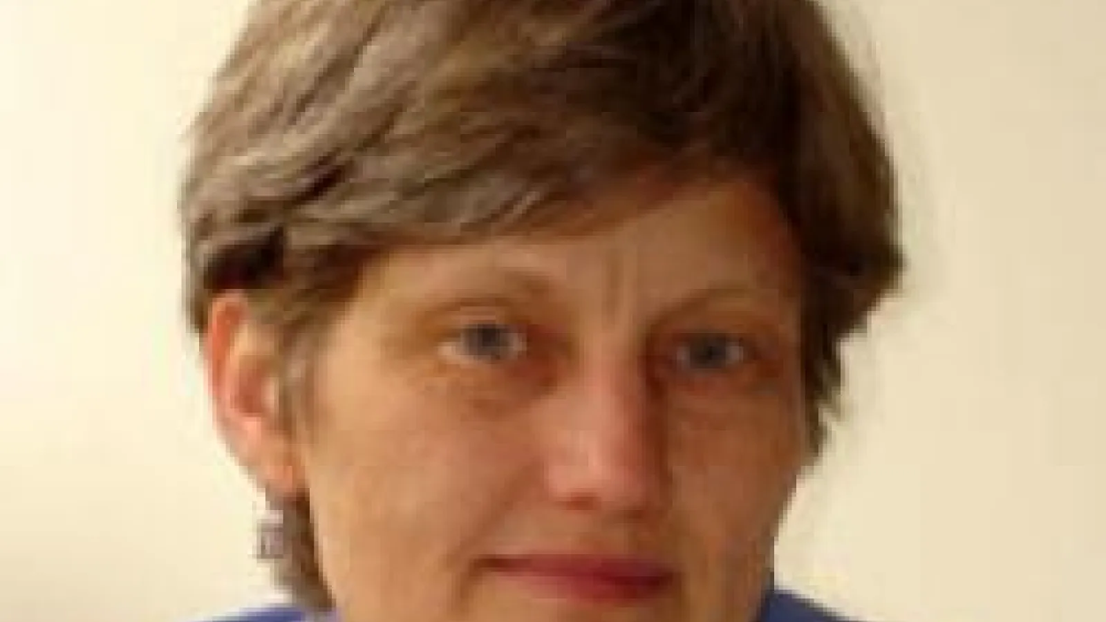 A close-up of  Lisbeth Gronlund with a beige background.